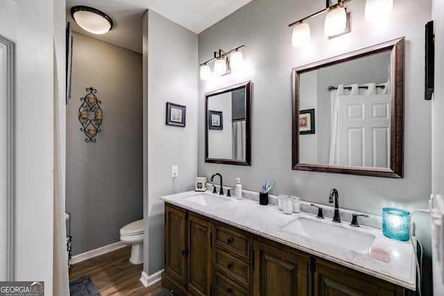 full bath with double vanity, a sink, wood finished floors, and toilet