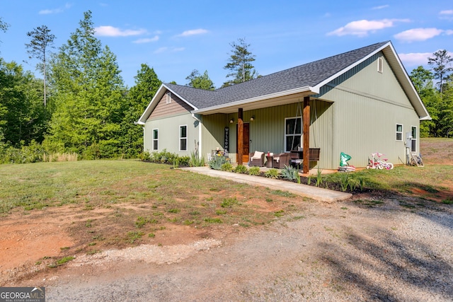 ranch-style house with a porch, a shingled roof, and a front lawn