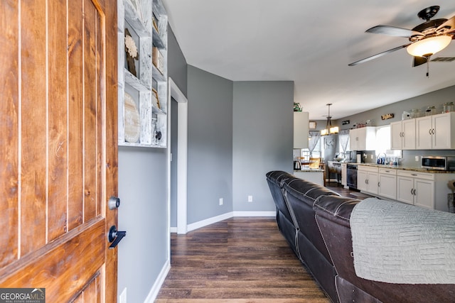 living room with dark wood-type flooring, baseboards, ceiling fan, and visible vents