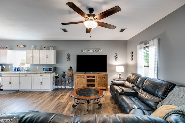living area with ceiling fan, wood finished floors, and visible vents