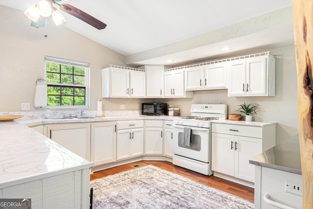 709 Tallapoosa Hwy, Cedartown, GA 30125 - kitchen with a sink, white gas range oven, white cabinetry, and lofted ceiling