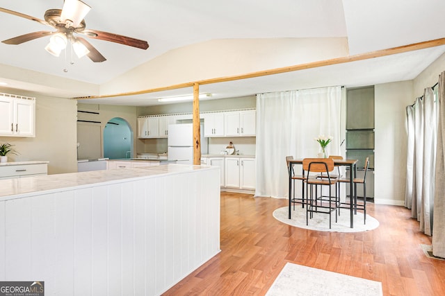 709 Tallapoosa Hwy, Cedartown, GA 30125 - kitchen with freestanding refrigerator, arched walkways, white cabinets, and lofted ceiling