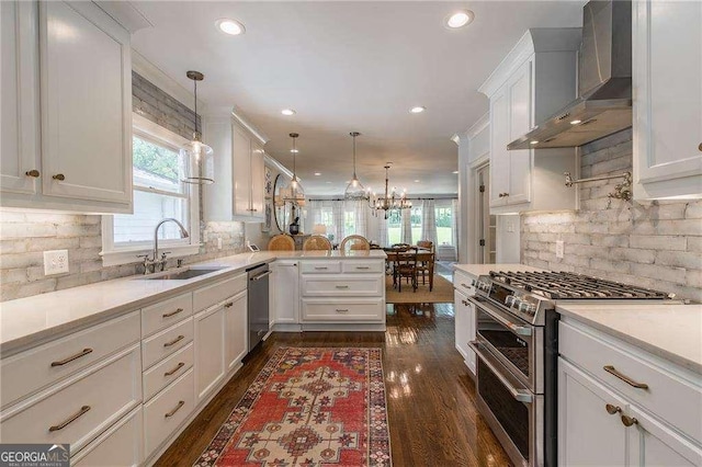 kitchen featuring plenty of natural light, a sink, wall chimney exhaust hood, and appliances with stainless steel finishes