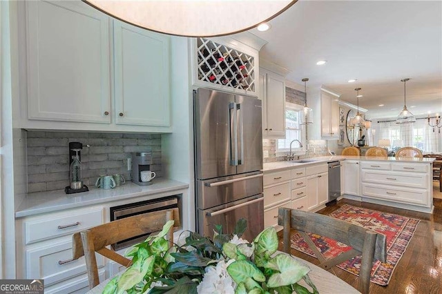 kitchen featuring a healthy amount of sunlight, stainless steel appliances, a peninsula, and a sink