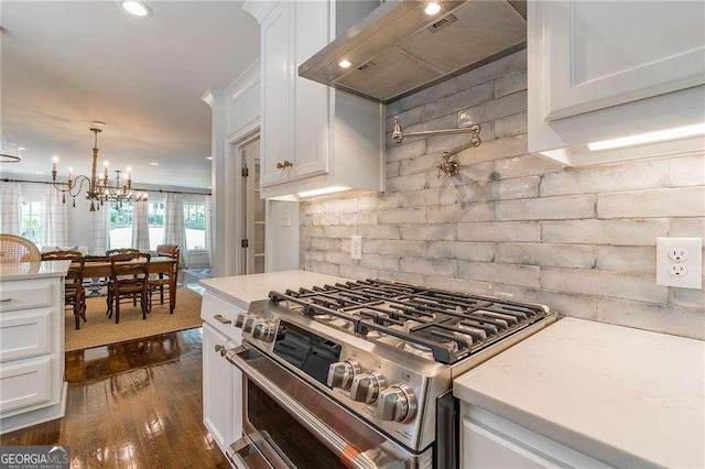 kitchen featuring white cabinets, light countertops, wall chimney exhaust hood, stainless steel range with gas cooktop, and dark wood-style floors