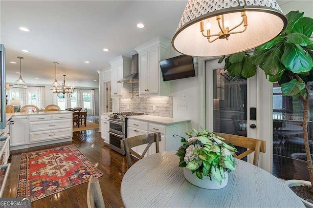 kitchen with recessed lighting, wall chimney exhaust hood, white cabinets, a notable chandelier, and double oven range