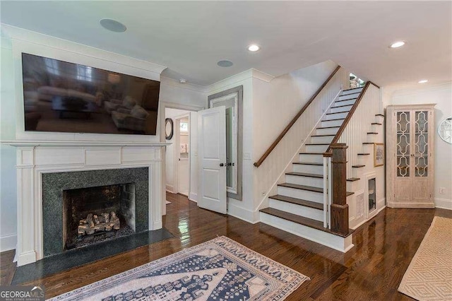 living area with stairs, ornamental molding, wood finished floors, and a high end fireplace