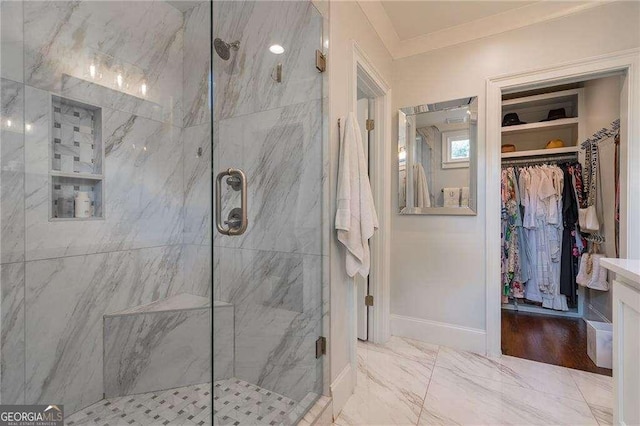 full bathroom featuring a marble finish shower, ornamental molding, baseboards, and a spacious closet
