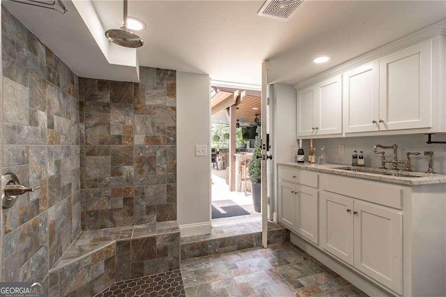 interior space with visible vents, vanity, recessed lighting, stone finish flooring, and a tile shower