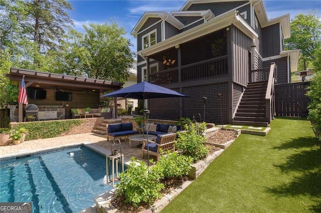 rear view of house featuring a patio, an outdoor kitchen, stairs, a fenced in pool, and a yard