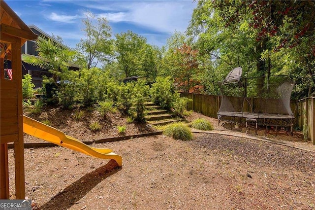 view of yard with a fenced backyard, a trampoline, and a playground