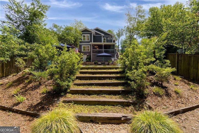 rear view of property with a fenced backyard, stairs, and a balcony