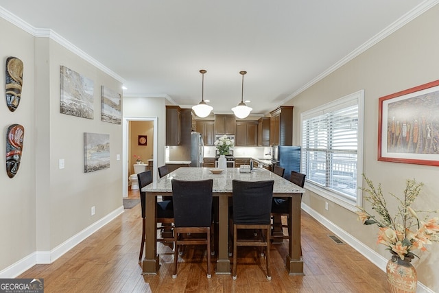 55 Sudderth St, Buford, GA 30518 - dining area with crown molding, baseboards, light wood finished floors, and visible vents