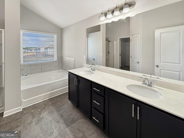 376 Layfield Dr, Jonesboro, GA 30238 - bathroom featuring double vanity, vaulted ceiling, a sink, and a garden tub