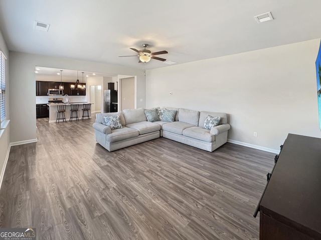 376 Layfield Dr, Jonesboro, GA 30238 - living room with baseboards, dark wood-style flooring, ceiling fan with notable chandelier, and visible vents
