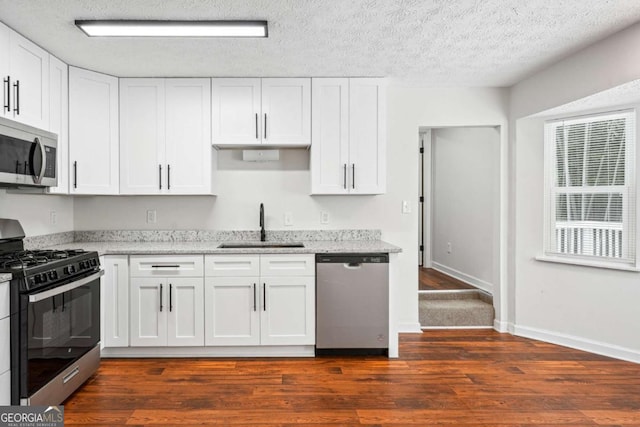 3688 Burnley Ct, Lithonia, GA 30038 - kitchen featuring white cabinets, light stone countertops, appliances with stainless steel finishes, a sink, and dark wood finished floors