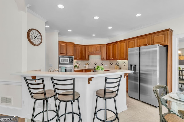 5303 Davenport Mnr, Cumming, GA 30041 - kitchen with visible vents, brown cabinets, a kitchen bar, and stainless steel appliances