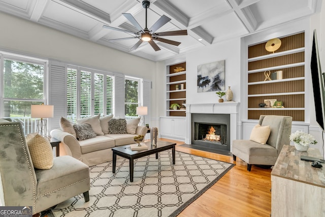 5303 Davenport Mnr, Cumming, GA 30041 - living room with ceiling fan, built in shelves, beam ceiling, a warm lit fireplace, and light wood-style flooring