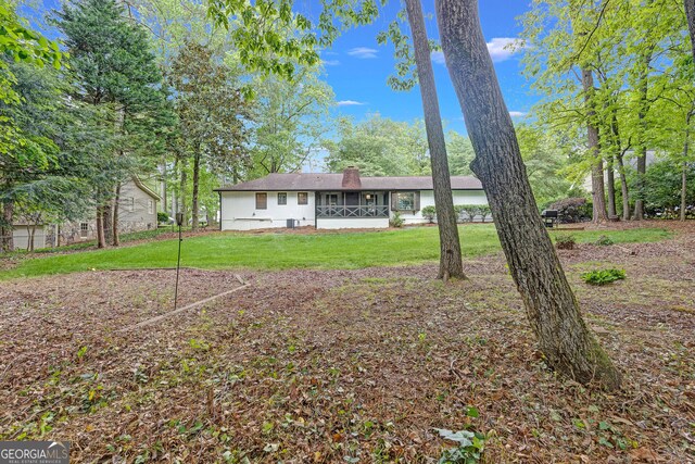 back of house with a chimney and a yard