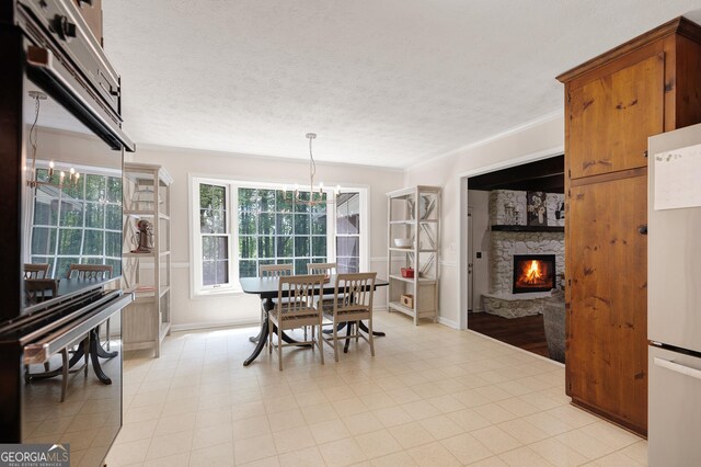 dining space featuring a chandelier, a fireplace, baseboards, ornamental molding, and a textured ceiling