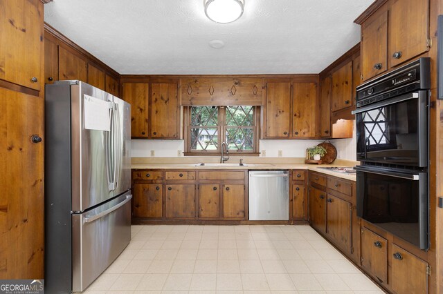 kitchen with appliances with stainless steel finishes, light countertops, brown cabinets, and a sink