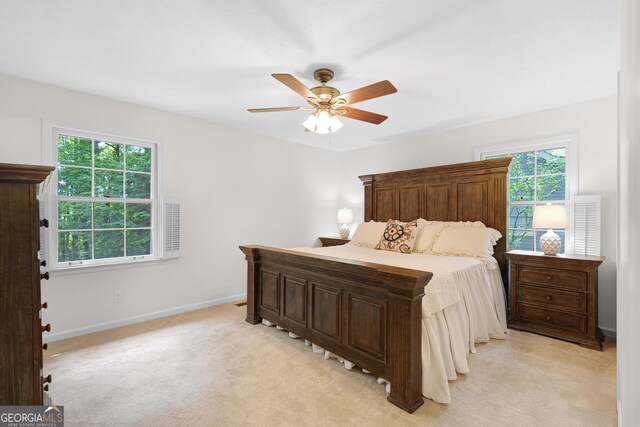 bedroom featuring multiple windows, baseboards, light carpet, and ceiling fan