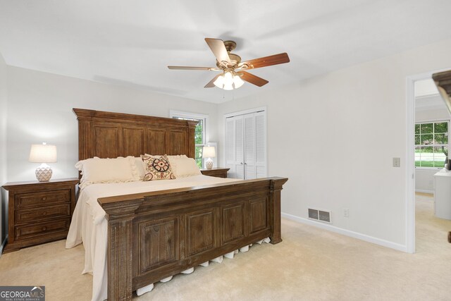 bedroom featuring light colored carpet, baseboards, ceiling fan, and a closet