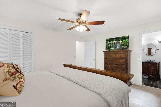 bedroom with a sink, a closet, light carpet, a ceiling fan, and ensuite bath