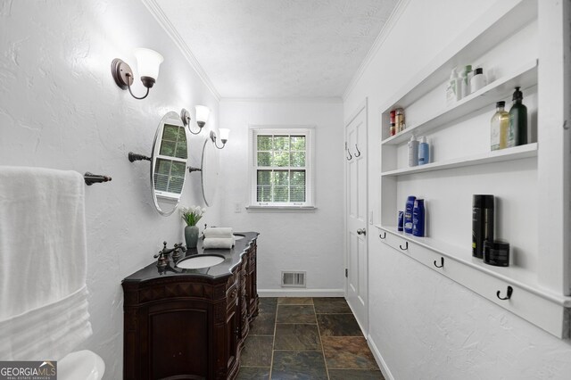 bathroom featuring ornamental molding, stone finish floors, vanity, a textured ceiling, and baseboards