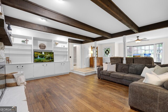 living room featuring hardwood / wood-style flooring, beam ceiling, ornate columns, and a ceiling fan
