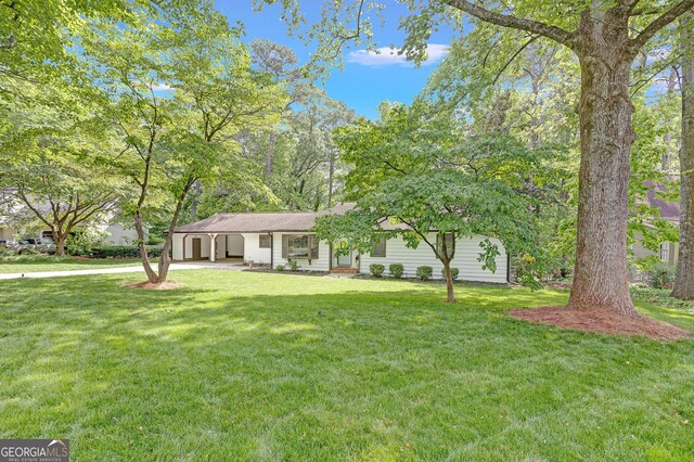 ranch-style home featuring a front lawn, concrete driveway, and an attached carport