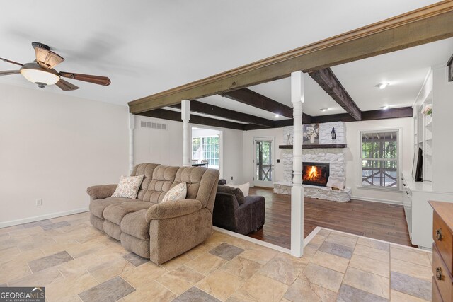 living room featuring baseboards, a fireplace, beam ceiling, ornate columns, and a ceiling fan