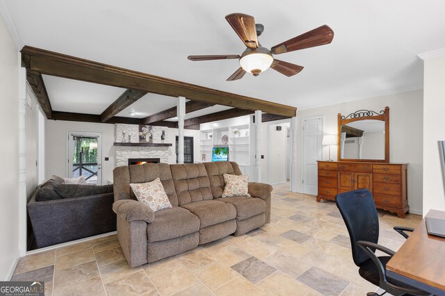 living area with ceiling fan, light stone finish floors, a stone fireplace, beam ceiling, and a desk
