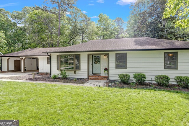ranch-style home featuring a front lawn, a shingled roof, and an attached garage