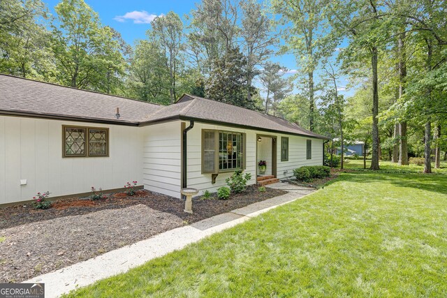 ranch-style house with a front yard and a shingled roof