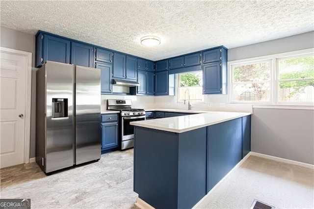 848 E Ave, Scottdale, GA 30079 - kitchen featuring appliances with stainless steel finishes, light countertops, a peninsula, under cabinet range hood, and blue cabinets