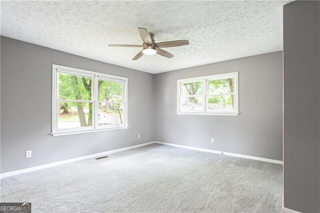 848 E Ave, Scottdale, GA 30079 - carpeted empty room with plenty of natural light, a ceiling fan, baseboards, and a textured ceiling