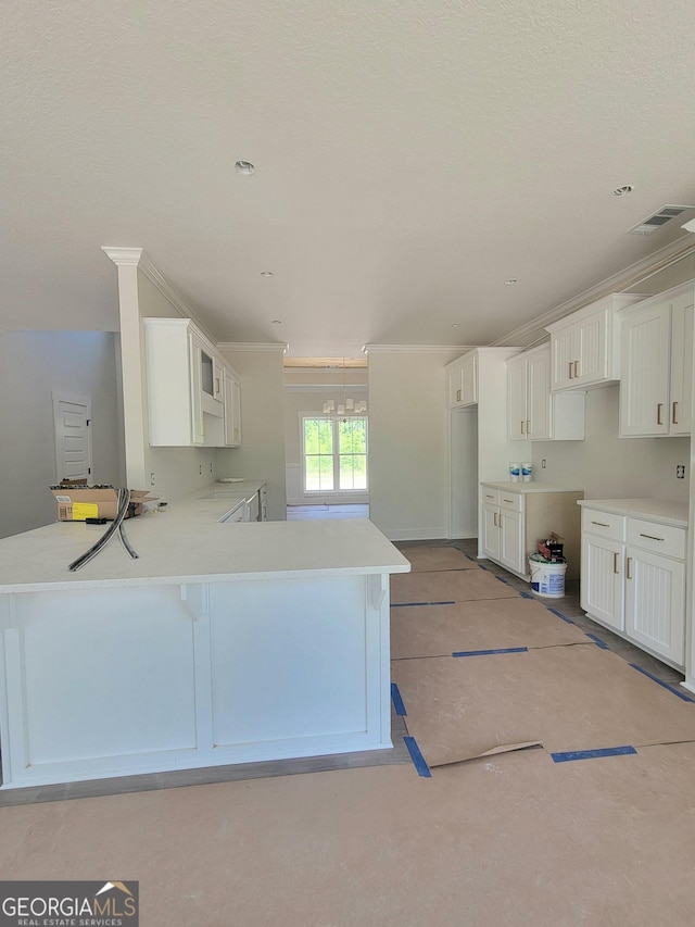 kitchen featuring crown molding, visible vents, a peninsula, a breakfast bar area, and white cabinetry