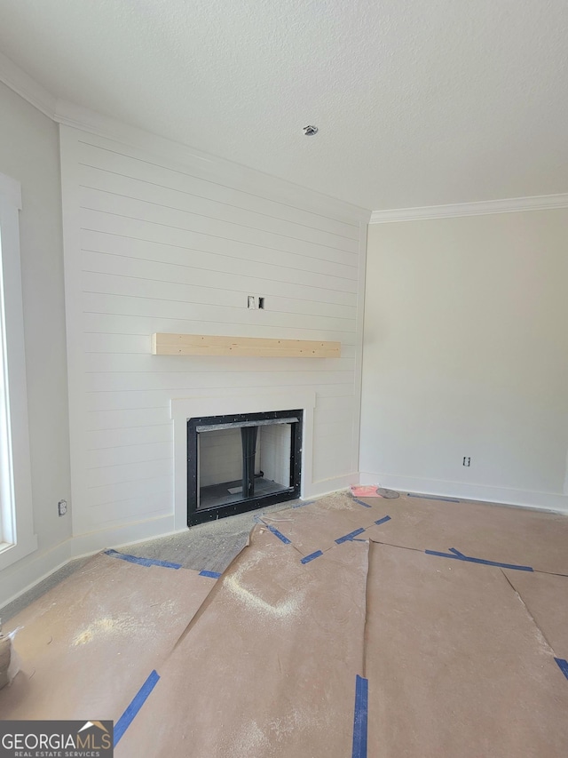 unfurnished living room featuring crown molding, a large fireplace, baseboards, and a textured ceiling