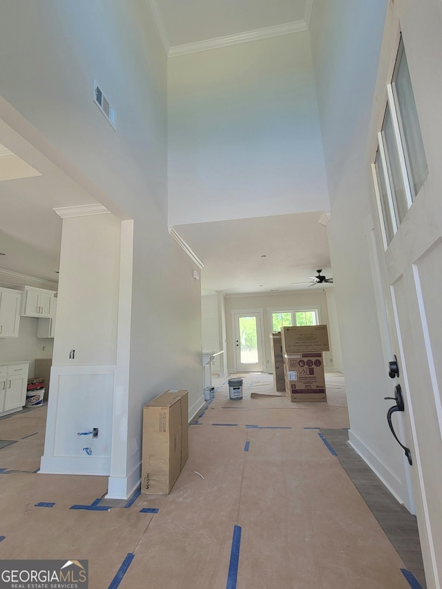 foyer entrance featuring a high ceiling, ornamental molding, a ceiling fan, and visible vents