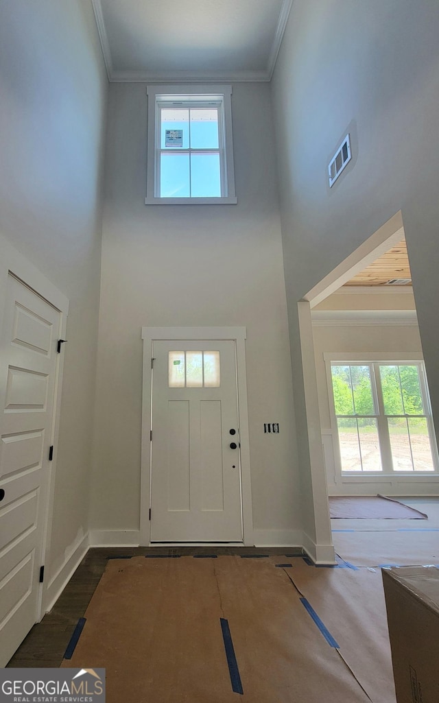 foyer entrance featuring visible vents, ornamental molding, and a towering ceiling