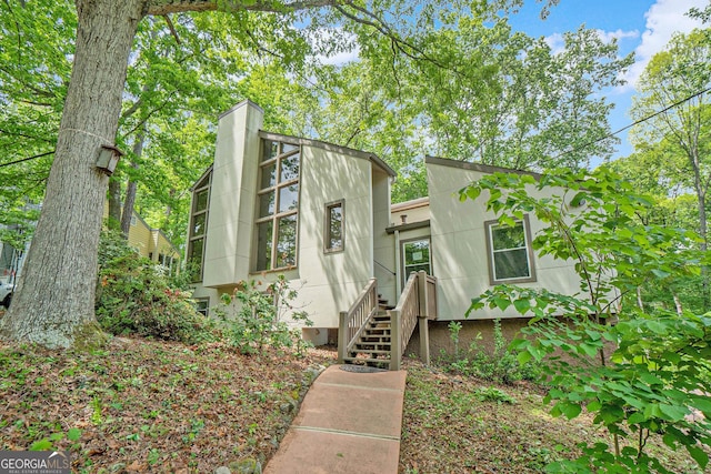 mid-century modern home with stucco siding and a chimney
