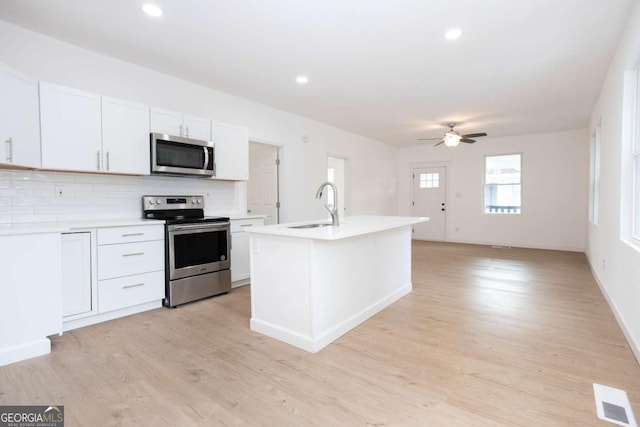 kitchen with ceiling fan, a sink, stainless steel appliances, decorative backsplash, and visible vents