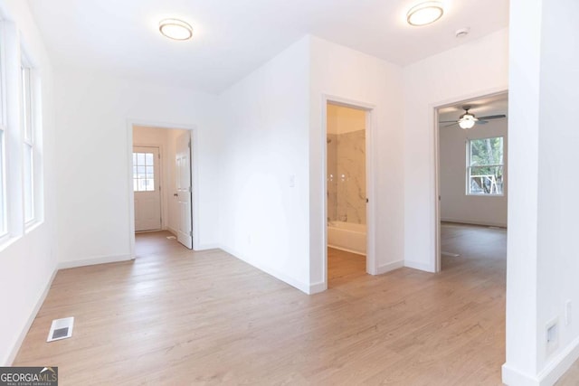 unfurnished room with a ceiling fan, baseboards, plenty of natural light, and light wood-type flooring