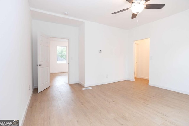 empty room featuring a ceiling fan, baseboards, visible vents, and light wood finished floors
