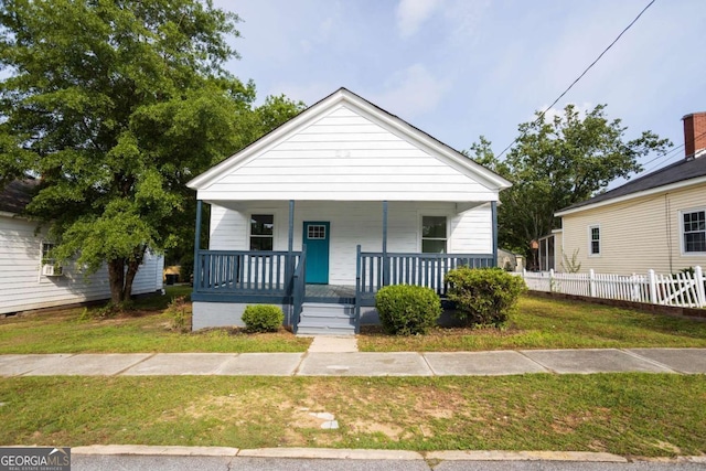 view of front of home featuring fence, a porch, and a front lawn