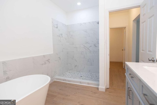 full bathroom with a freestanding tub, a stall shower, wood finished floors, vanity, and recessed lighting