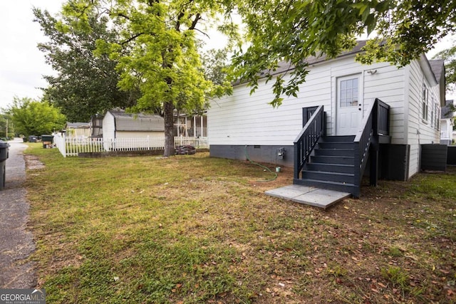 rear view of house with central AC unit, fence, a yard, and crawl space