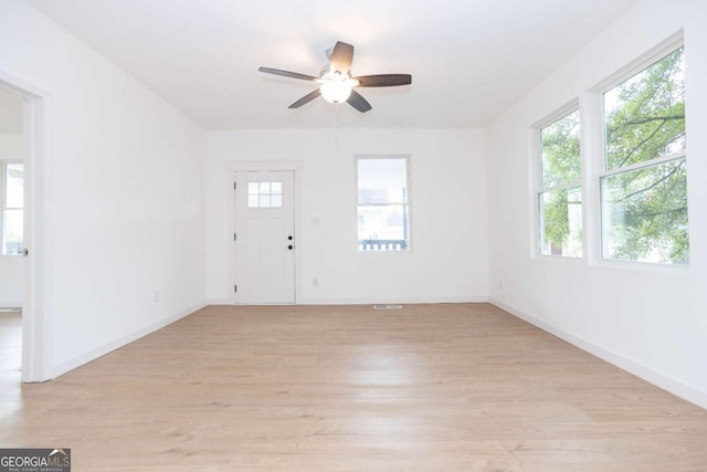interior space with baseboards, light wood-style flooring, ceiling fan, and visible vents