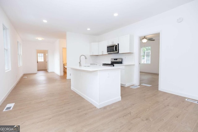 kitchen with visible vents, baseboards, light wood finished floors, stainless steel appliances, and white cabinetry